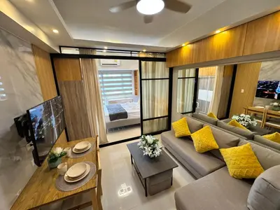 a living room with a gray couch and yellow pillows at Deluxe Room with Parking in Red Residences Chino Roces Ave, Makati by Prime Stay in Manila