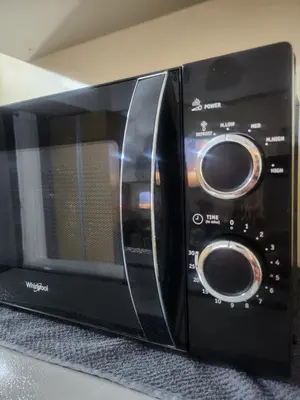 a black microwave oven sitting on top of a counter at Owls and Larks BnB 300mbps WiFi, Netflix, Coffee in Manila