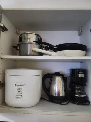 a kitchen shelf with pots and pans and a coffee maker at Owls and Larks BnB 300mbps WiFi, Netflix, Coffee in Manila