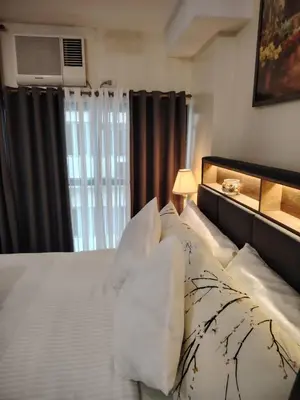 a bedroom with a bed with white sheets and a window at Owls and Larks BnB 300mbps WiFi, Netflix, Coffee in Manila
