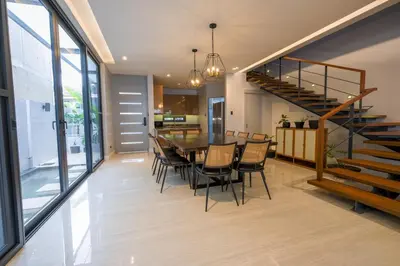 a dining room with a table and chairs and a staircase at Casa Bonifacio by JC in Manila