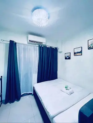 a bedroom with a bed with blue curtains and a window at La Deza Shore 2 Residences Pasay Manila in Manila