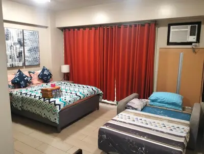 a bedroom with a bed and a red curtain at Nadzcondotel 2- at Two Palm Tree Villas o in Manila