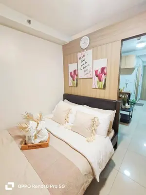 two beds in a bedroom with a clock on the wall at MOA Exquisite Suite Manila by JAO's Staycation in Manila