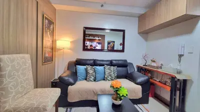 a living room with a couch and a mirror at MOA Exquisite Suite Manila by JAO's Staycation in Manila