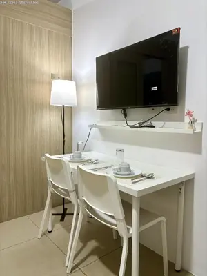 a white table with chairs and a television on a wall at New Oasis Staycation Shore 1 in Manila