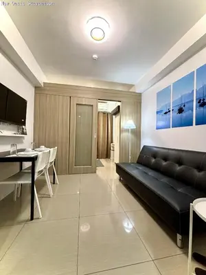 a living room with a black couch and a dining room at New Oasis Staycation Shore 1 in Manila