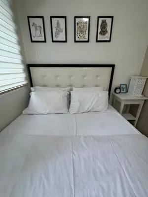 a bedroom with a white bed with four pictures on the wall at Homey 1 Bedroom Condo with Blacony and Wifi in Manila