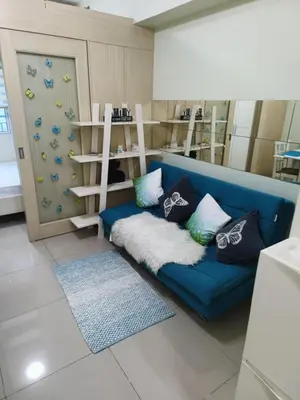 a living room with a blue couch with pillows at Homey 1 Bedroom Condo with Blacony and Wifi in Manila