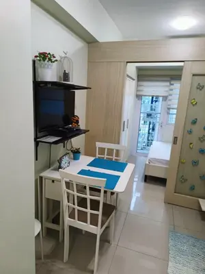 a dining room with a table and a television at Homey 1 Bedroom Condo with Blacony and Wifi in Manila