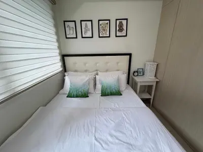 a bedroom with a white bed with two green pillows at Homey 1 Bedroom Condo with Blacony and Wifi in Manila