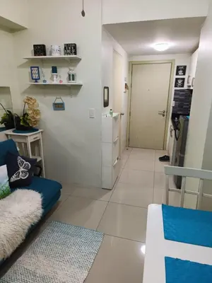 a living room with a blue couch and a door at Homey 1 Bedroom Condo with Blacony and Wifi in Manila