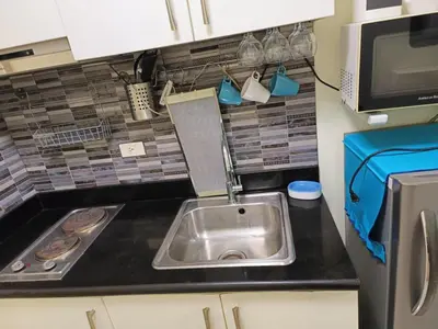 a small kitchen with a sink and a microwave at Homey 1 Bedroom Condo with Blacony and Wifi in Manila