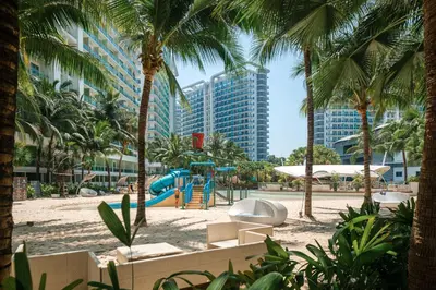 a playground in a resort with palm trees and a building at Azure Urban Resort Residences Parañaque City in Manila