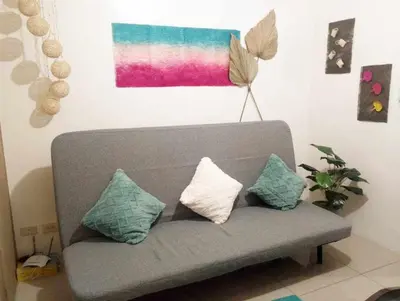 a gray couch with pillows in a living room at Shore Residences by Casa Stellar in Manila