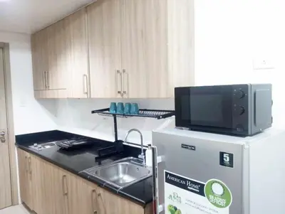 a small kitchen with a sink and a tv on top of a refrigerator at Shore Residences by Casa Stellar in Manila