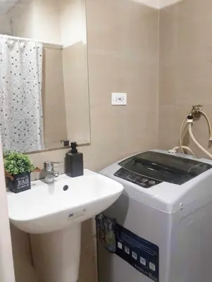 a bathroom with a sink and a washing machine at Shore Residences by Casa Stellar in Manila
