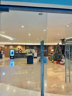 a glass door in a lobby with a christmas tree at Crystal Cove by Casa Stellar Mall of Asia Complex in Manila