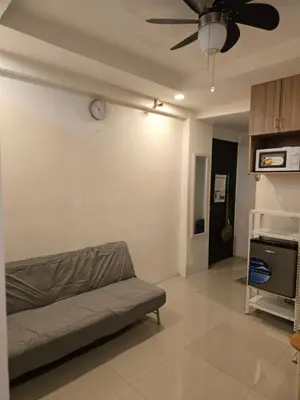 a living room with a couch and a clock on the wall at Homey Airport bnb 1BR w Wi-Fi in Manila