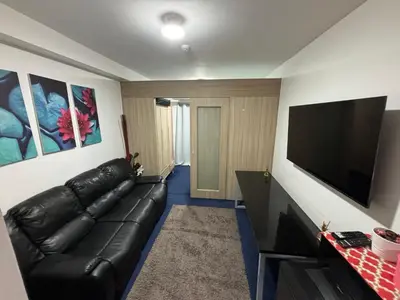 a living room with a black leather couch and a flat screen tv at MOA Home Away From Home in Manila