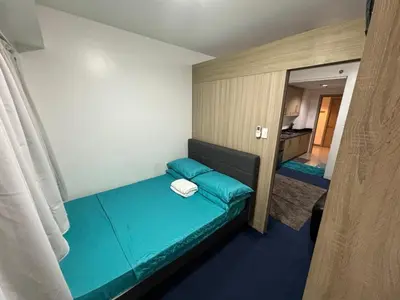 a small room with a blue bed with a mirror at MOA Home Away From Home in Manila