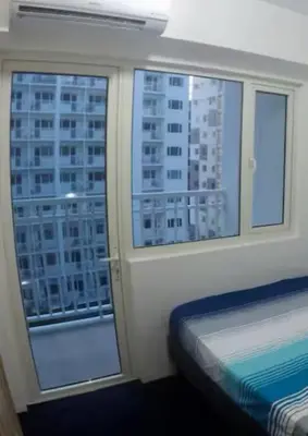 a bedroom with a window with a view of a city at MOA Home Away From Home in Manila