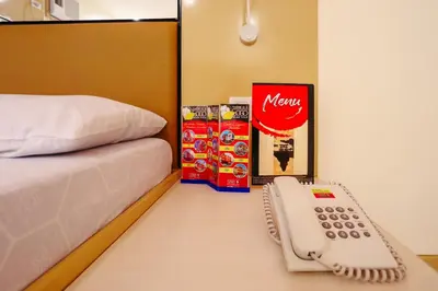 a phone sitting on a table next to a bed at Hotel Sogo Dasmariñas Cavite in Dasmariñas