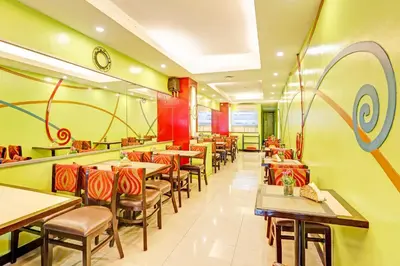 a restaurant with tables and chairs and a clock on the wall at Collection O VIP Suites, Near PNR Pasay Evangelista, Makati Manila in Manila