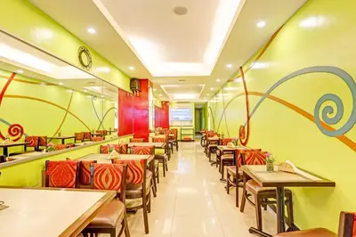 a restaurant with tables and chairs and a clock on the wall at Collection O VIP Suites, Near PNR Pasay Evangelista, Makati Manila in Manila