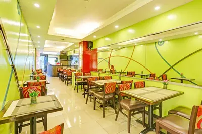 a restaurant with tables and chairs and green walls at Collection O VIP Suites, Near PNR Pasay Evangelista, Makati Manila in Manila