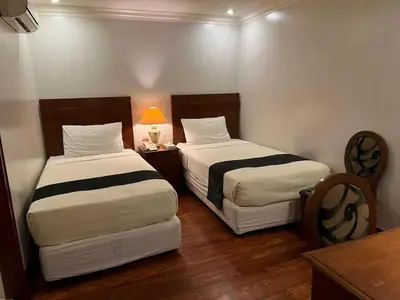 two beds in a small room with a table and a bed sidx sidx at Collection O VIP Suites, Near PNR Pasay Evangelista, Makati Manila in Manila