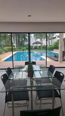a glass table and chairs and a swimming pool at Minimalist Studio Condo - Alabang Near Airport in Manila