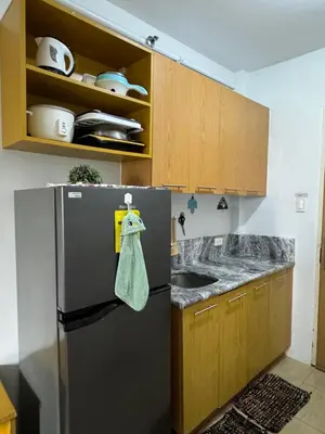 a kitchen with a stainless steel refrigerator and wooden cabinets at Minimalist Studio Condo - Alabang Near Airport in Manila
