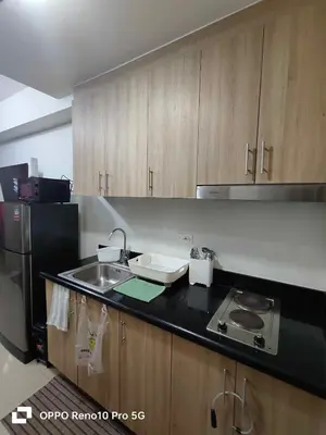 a kitchen with wooden cabinets and a sink and a refrigerator at G Spot Manila - Mall of Asia in Manila