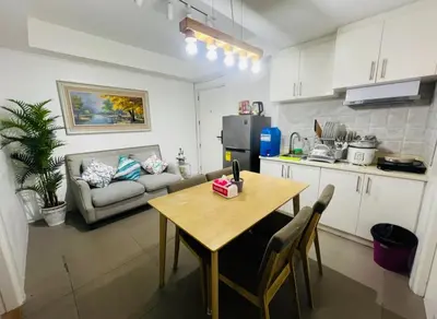 a kitchen and dining room with a table and a couch at Porto Vita 2BR in Manila
