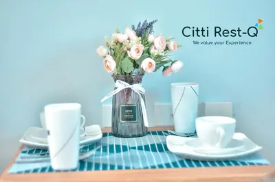 a table with a vase of flowers and two cups at Studio City Alabang Pool Access Free for 2 Wifi & Netflix SC2 in Manila