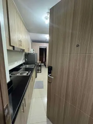 a kitchen with wooden cabinets and a black counter top at Mall of Asia Staycation by Mochi - SMDC Shore 2 Tower 3 in Manila