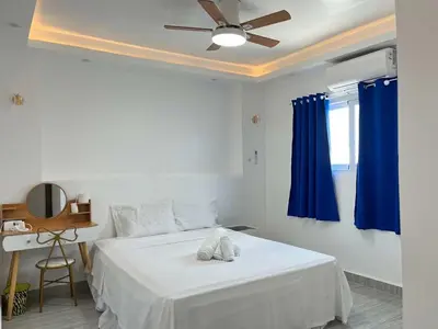 a bedroom with a bed with blue curtains and a ceiling fan at Shiri Pool Villa 1 in Silang
