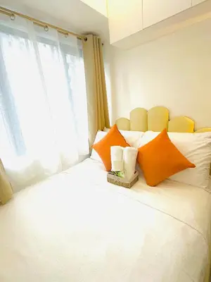 a white bed with orange pillows and a window at Ustays in comfort and style in Manila
