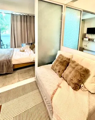 a bedroom with a couch and a bed and windows at Metroshore Azure 2 in Manila