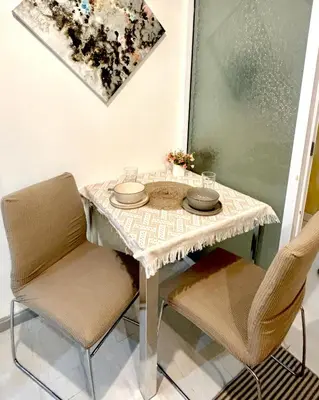 a table with two chairs and a table and a painting at Metroshore Azure 2 in Manila