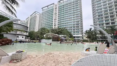 a swimming pool in a resort with people in the water at Metroshore Azure 2 in Manila