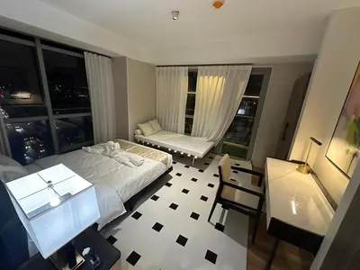 a bedroom with a bed and a window with a chair at Luxurious Modern Penthouse 2BR Cross City of Dreams OKADA SOLAIRE MOA Airports in Manila