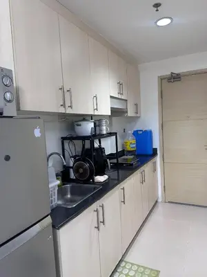 a kitchen with white cabinets and a sink and a refrigerator at Minamalist modern Condo with Chic touches 