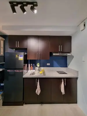 a kitchen with brown cabinets and a counter top at AD Camp in Manila