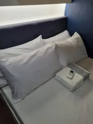a bed with white sheets and a book on it at AD Camp in Manila