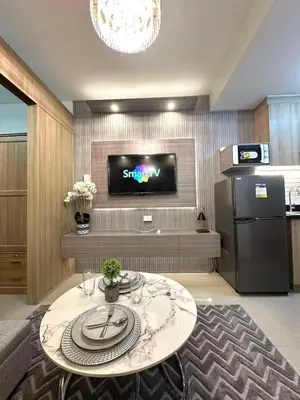 a living room with a table and a flat screen tv at Shore 2 Residences, 1BR Balcony - Pool view in Manila
