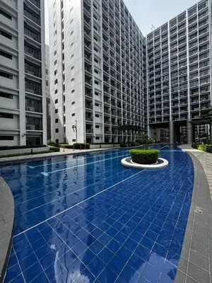 a swimming pool in the middle of two tall buildings at Shore 2 Residences, 1BR Balcony - Pool view in Manila