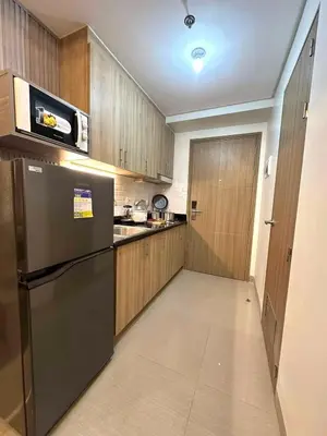 a kitchen with a stainless steel refrigerator and wooden cabinets at Shore 2 Residences, 1BR Balcony - Pool view in Manila