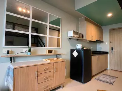 a kitchen with a black refrigerator and wooden cabinets at Condo Unit at SMDC Breeze Residences with a view in Manila